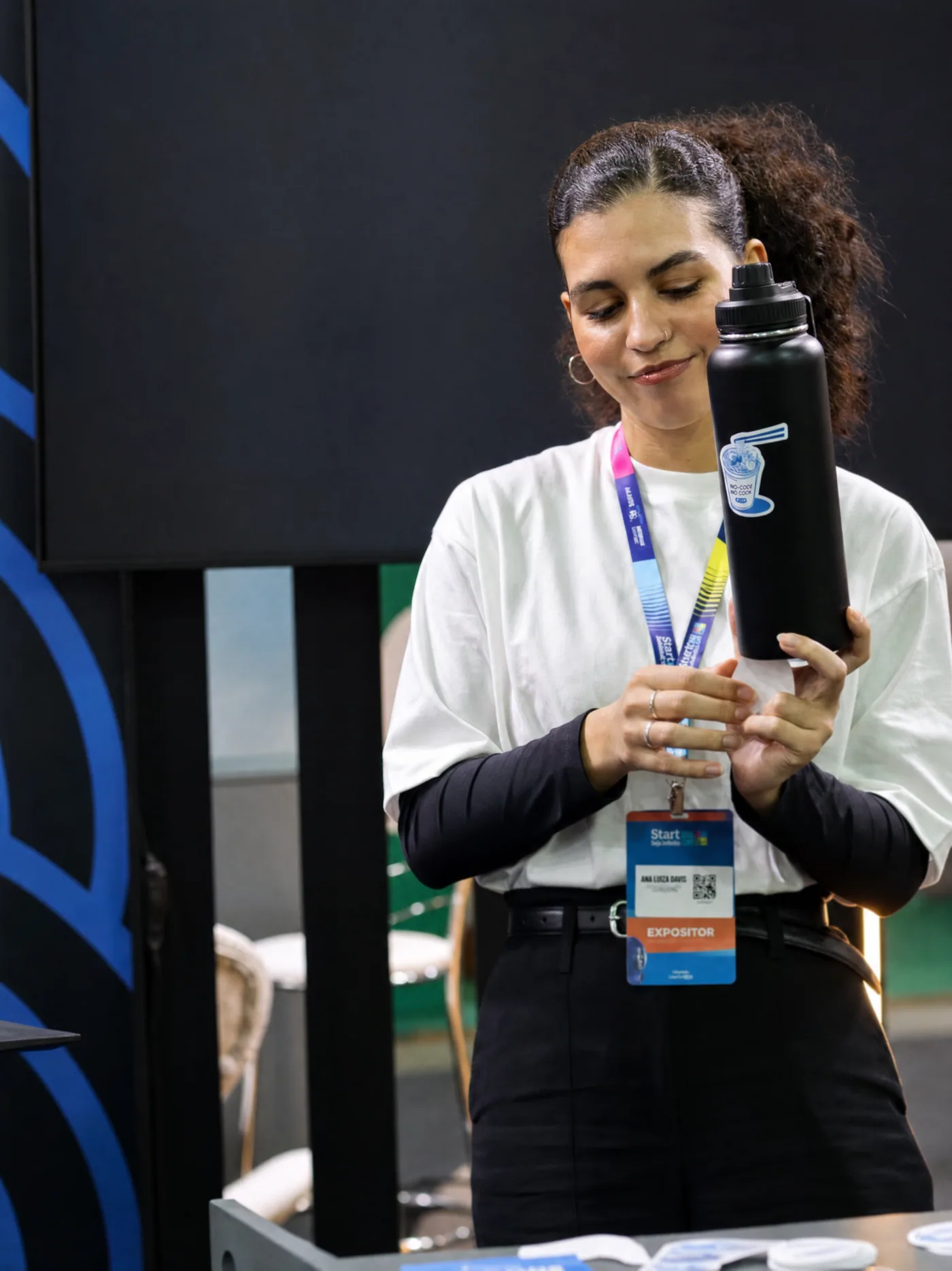 Integrante da equipe no estande com garrafa personalizada